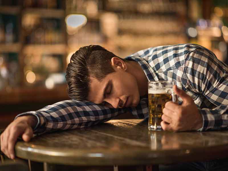 一个年轻的醉汉睡在酒吧的桌子上